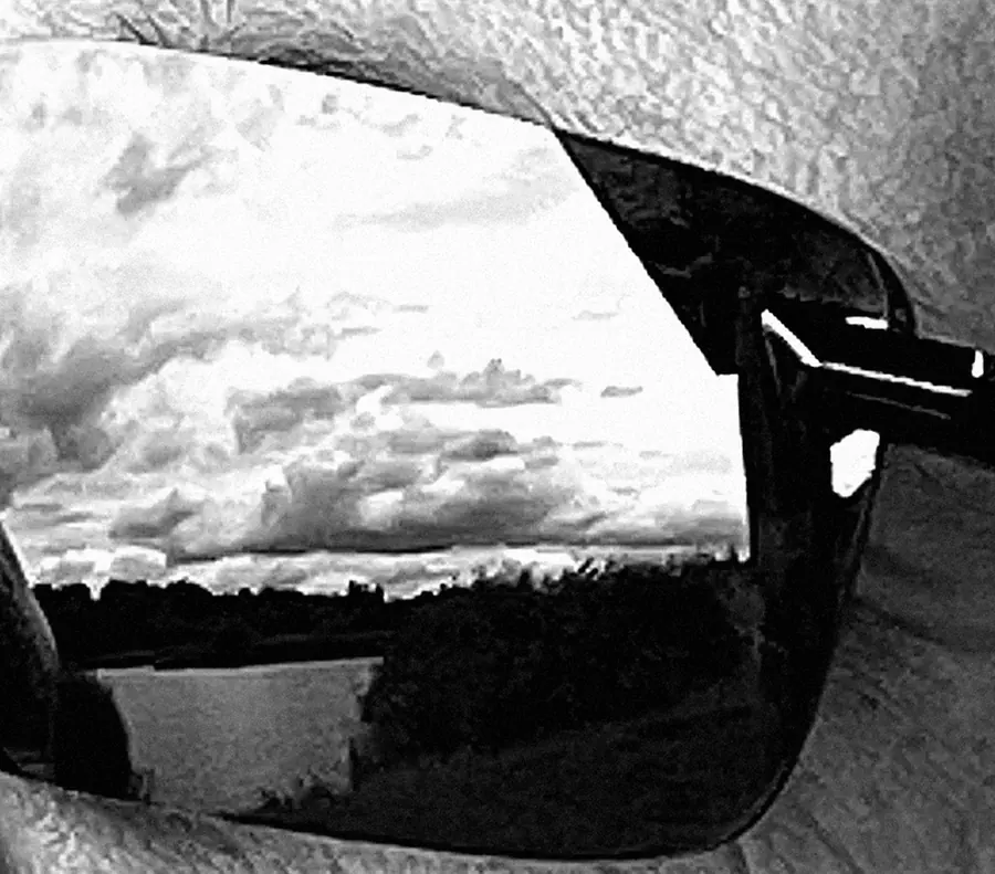 Close-up of Jacek’s sunglasses: a flat landscape with clouds and a lake reflected in the lens