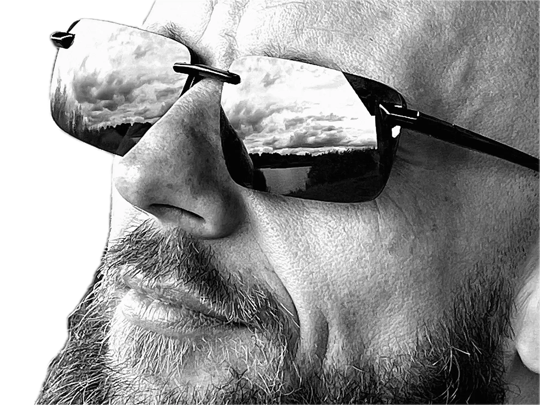 Black-and-white portrait of Jacek Grecki in rimless sunglasses, a cloudy sky reflected in the lenses